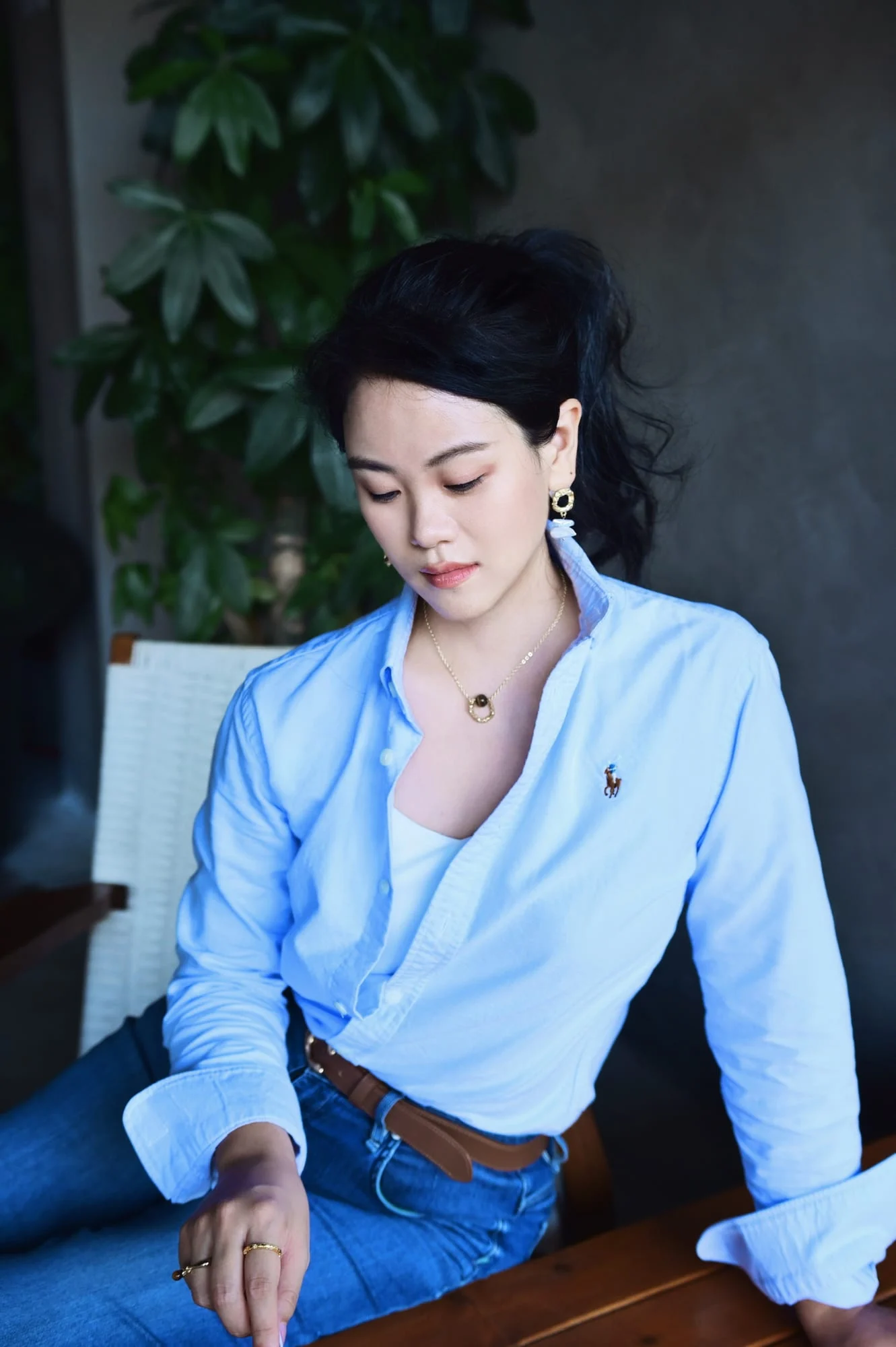 The ring pendant necklace worn by a model in a pale-blue shirt, seated and looking down.