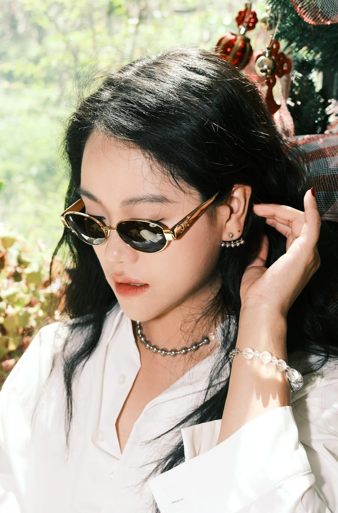 The clear bead bracelet catching the sunlight on the model’s raised wrist, its silver-toned charm hanging below.