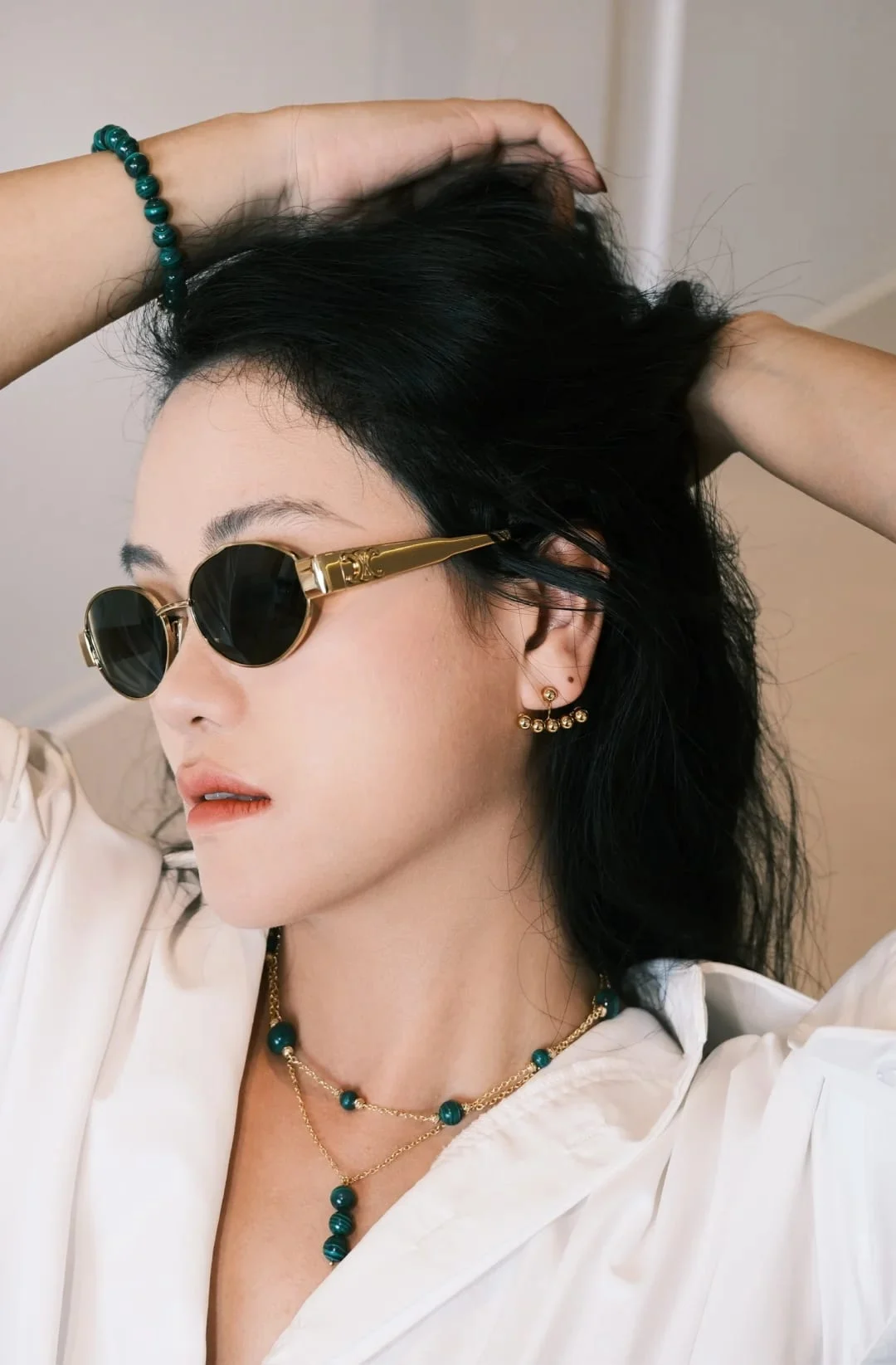 The three-bead drop necklace worn by a model in sunglasses, layered with the malachite station necklace.