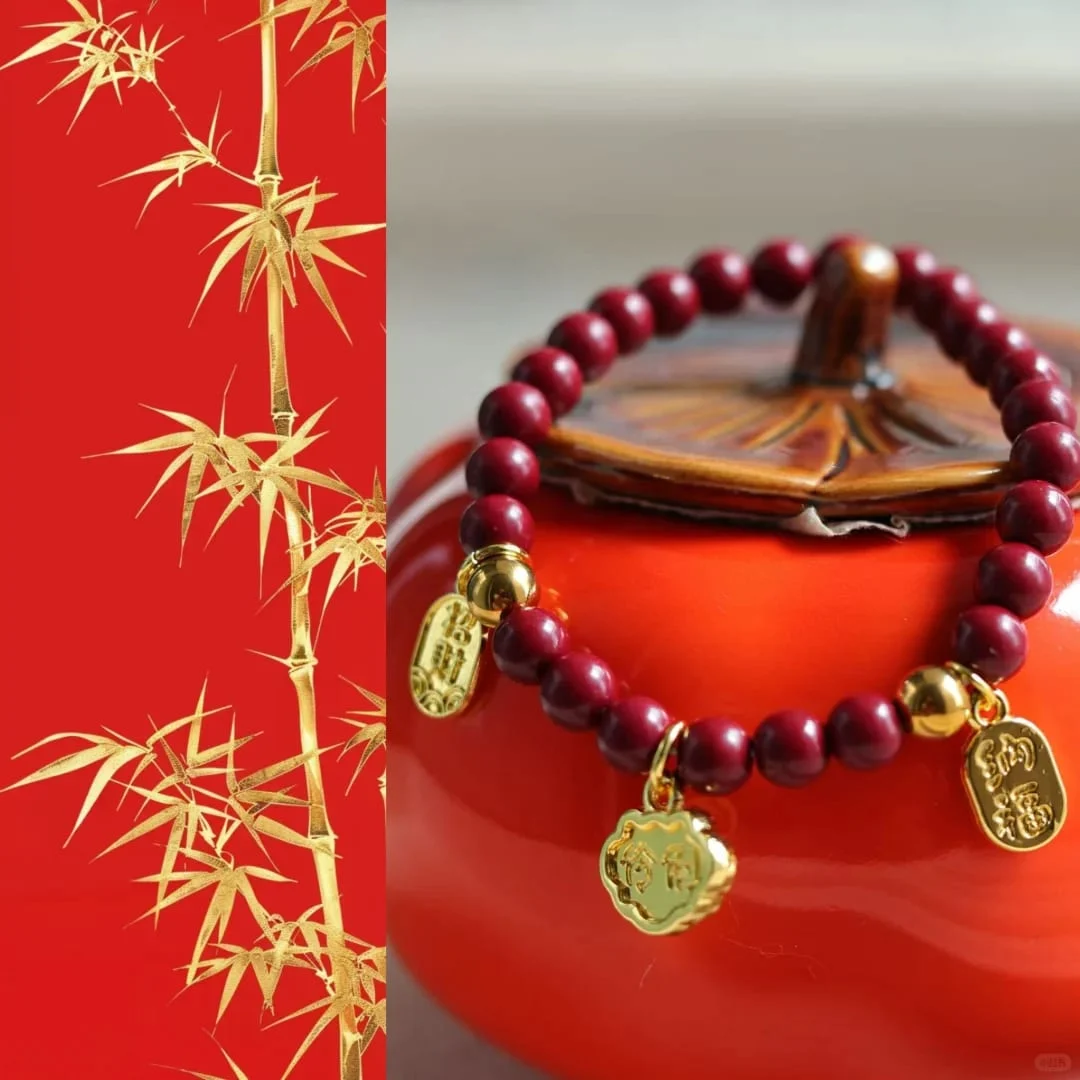 Bracelet of deep-red beads with gold-toned round beads and three small engraved gold-toned charms, resting on an orange ceramic jar.